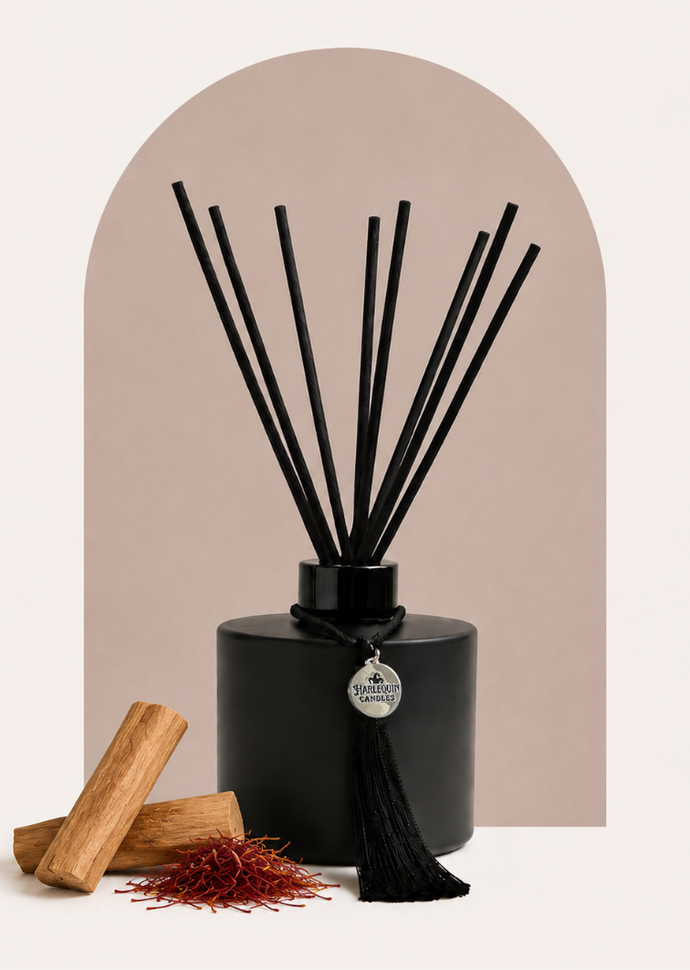 An Australian made Harlequin Candles reed diffuser with a warm and aromatic fragrance of saffron and sandalwood. The image shows the bottle on an orange background with sandalwood sticks and saffron flowers.