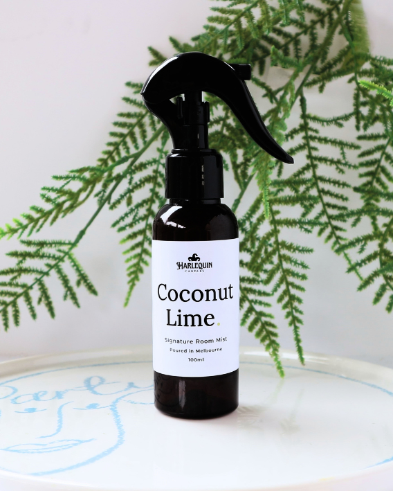 Tropical Coconut Lime luxury home fragrance spray styled with green fern leaves on a white designer tray, refreshing citrus room deodorizer by Harlequin Candles.