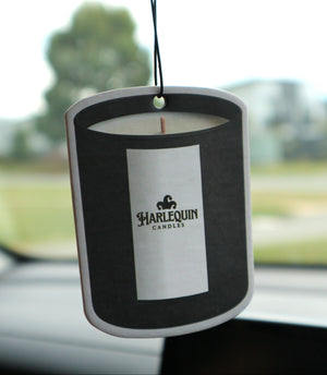 Harlequin Candles hanging car freshener suspended inside a car with the branded candle-shaped card in focus.
