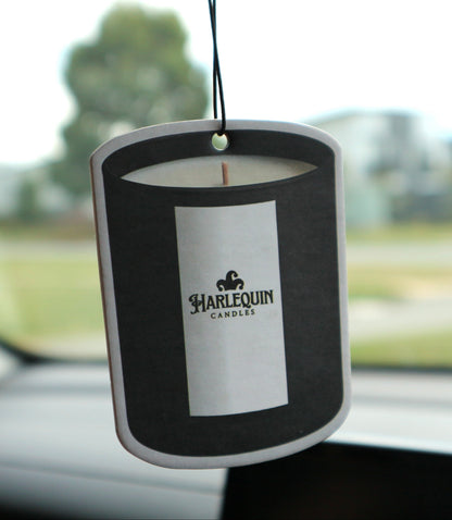 Harlequin Candles hanging car freshener suspended inside a car with the branded candle-shaped card in focus.