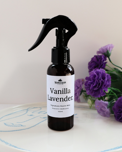 Luxury Vanilla Lavender home fragrance spray styled with purple carnations on a white designer tray, relaxing aromatherapy mist and linen spray by Harlequin Candles.